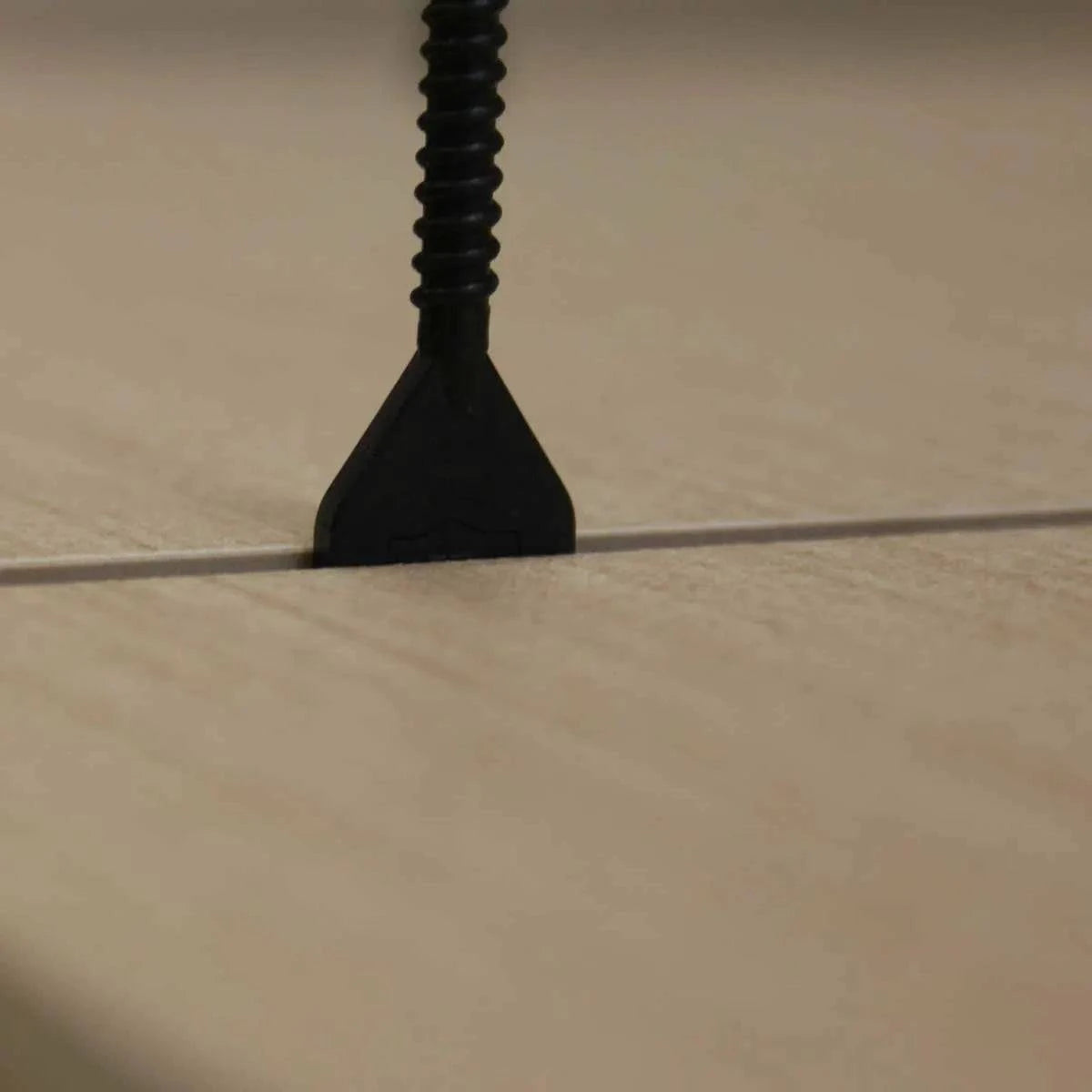 One tile adhesive has cured, use a rubbet mallet to remove the cap and threaded post from the installed tile