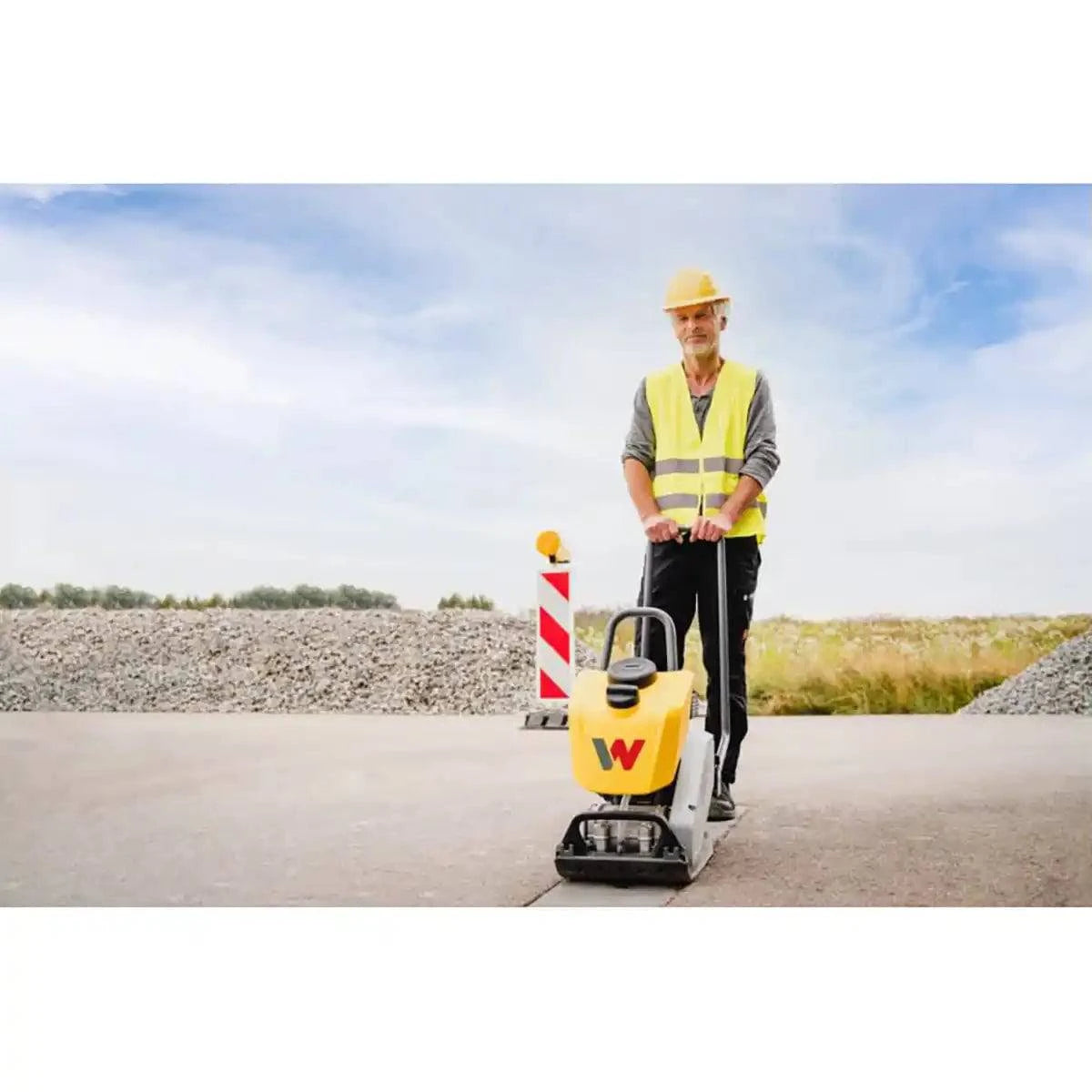 A worker operating a Wacker Neuson concrete plate on a construction site.